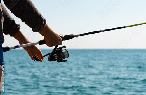 Fotografia Close-up of man holding a fishing rod near the sea.