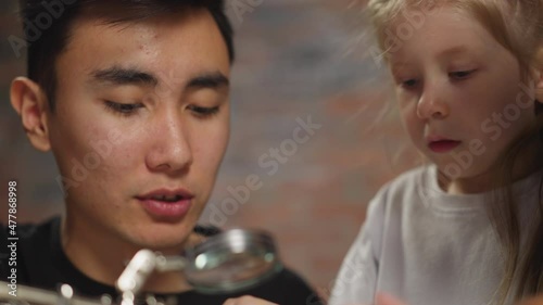 Young Asian teacher talks to girl student doing experiment photo