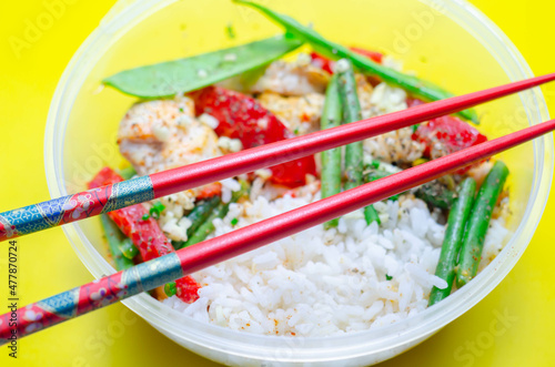 Cooked chicken breast pieces in a red Thai curry sauce made with coconut cream, red chillies, lemongrass, lime leaf, with fragrant rice, red peppers, mangetout, and green beans photo