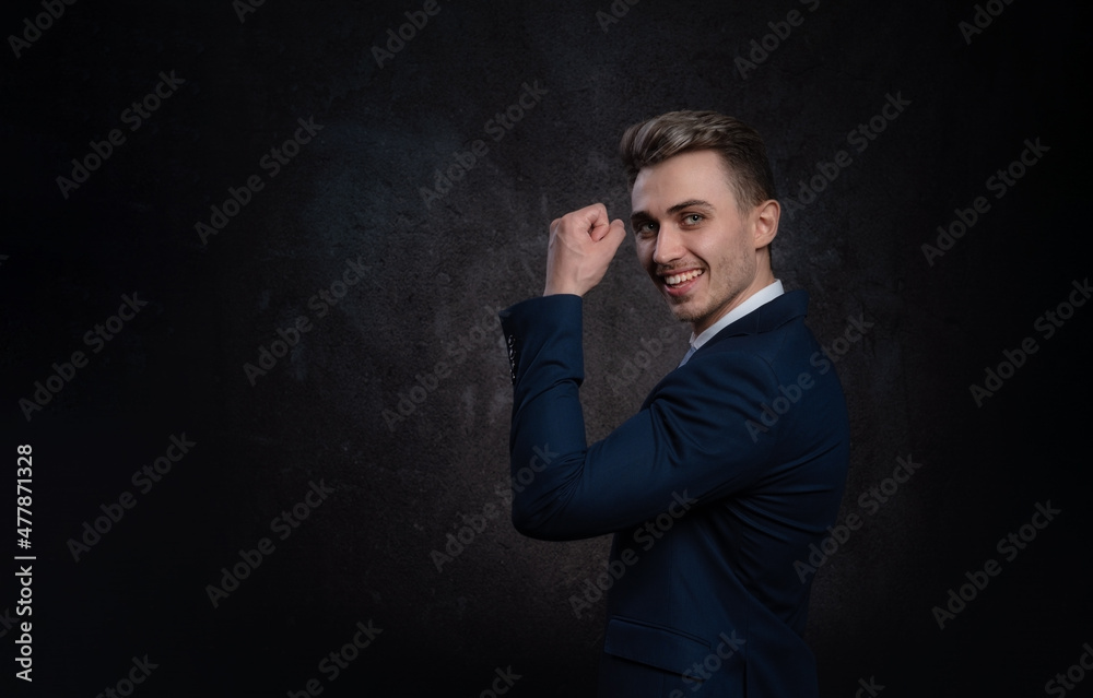 Emotional young business man in suit and tie celebrating victory with body gesture and whoop yes. On a black background. Copy space on left