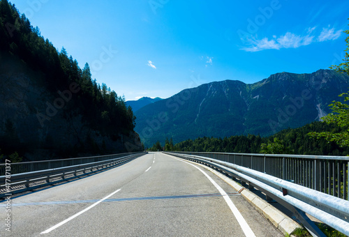 Panoramic view of a  road in summer landscape with fir trees and blue sky in the austrain alps against blue sky.