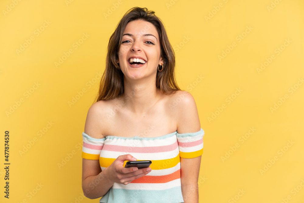 Young caucasian woman isolated on yellow background using mobile phone Young caucasian woman isolated on yellow background using mobile phone