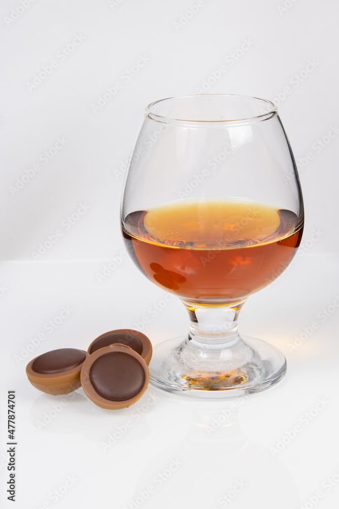 glass with cognac and chocolate on a white background