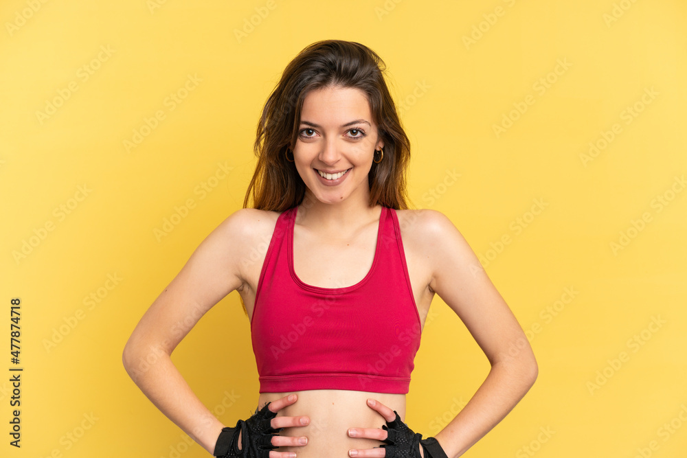 Young caucasian woman isolated on blue background posing with arms at hip and smiling