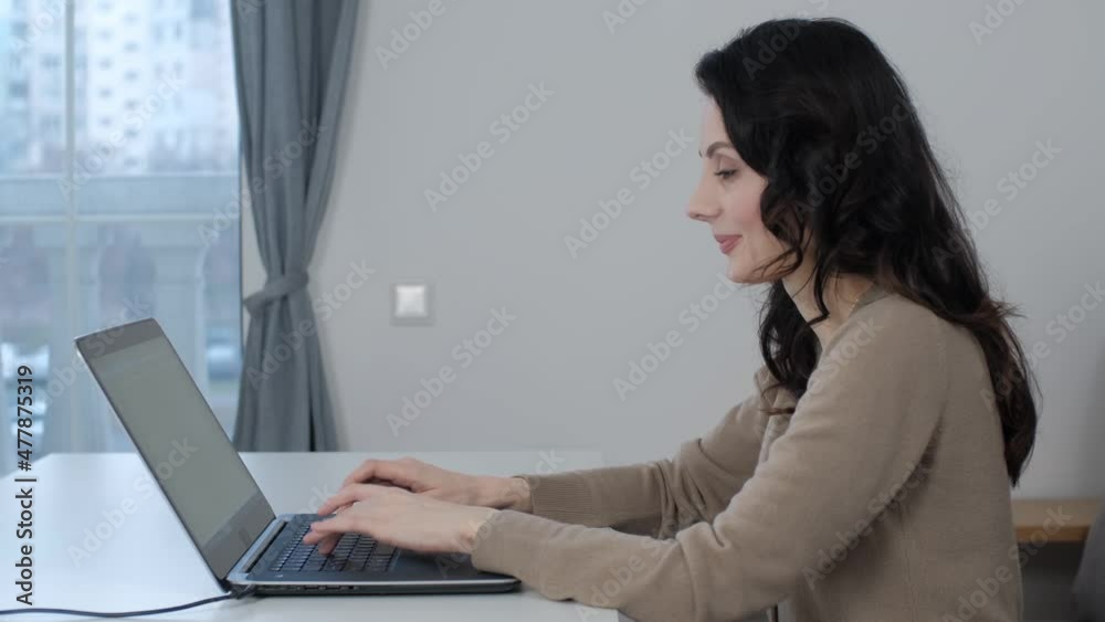 Freelancer woman working on laptop. Professioinal free lance writer typing text on notebook keyboard at home. Beautiful white female doing distant work on lockdown with cheerful smile Freelancer woman working on laptop. Professioinal free lance writer typing text on notebook keyboard at home. Beautiful white female doing distant work on lockdown with cheerful smile