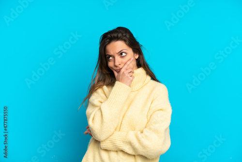 Young caucasian woman isolated on blue background having doubts and with confuse face expression