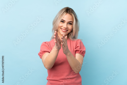 Teenager girl over isolated blue background applauding after presentation in a conference