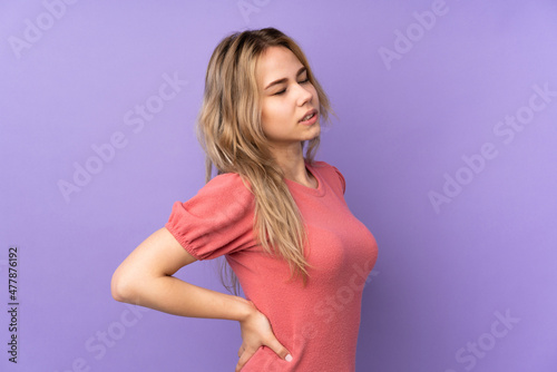 Teenager Russian girl isolated on purple background suffering from backache for having made an effort