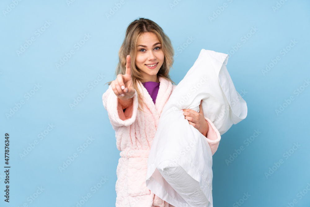 Teenager Russian girl in pajamas isolated on blue background showing and lifting a finger Teenager Russian girl in pajamas isolated on blue background showing and lifting a finger
