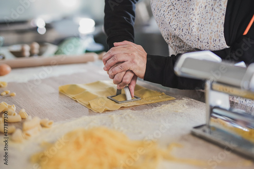 Woman working inside pasta factory and stamping fresh made ravioli