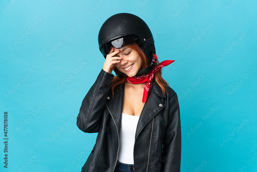Teenager biker girl isolated on blue background laughing Teenager biker girl isolated on blue background laughing