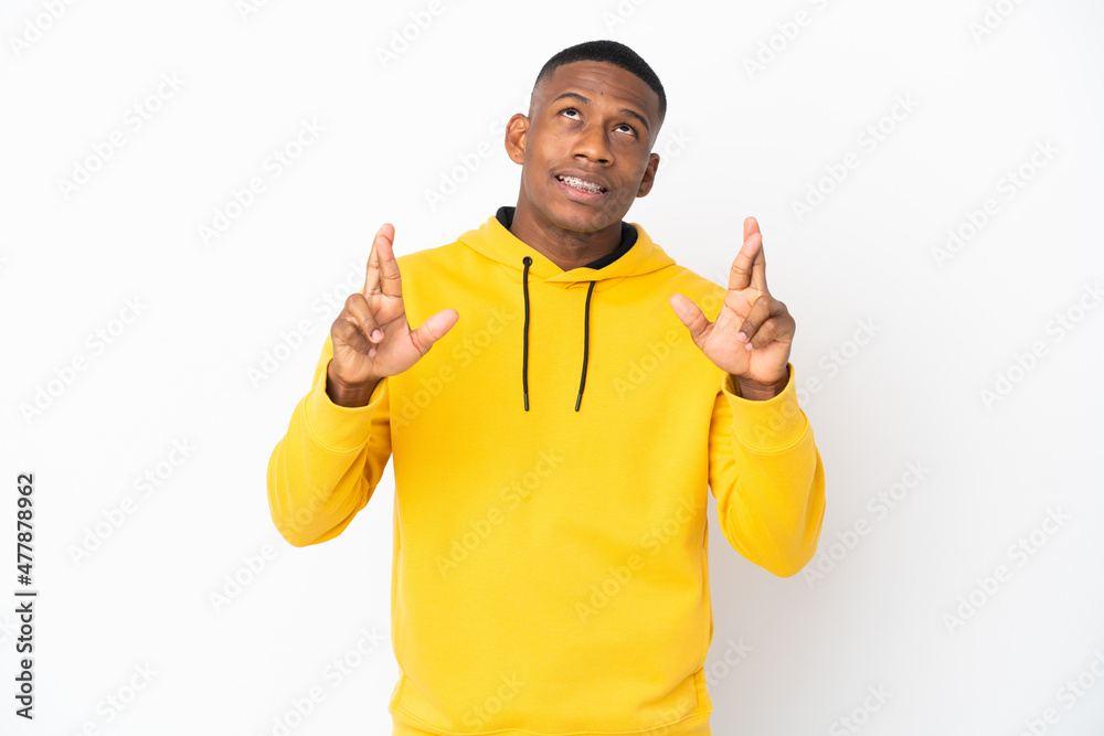 Young latin man isolated on white background with fingers crossing and wishing the best