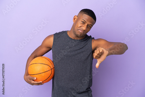Young basketball latin player man isolated on purple background showing thumb down with negative expression