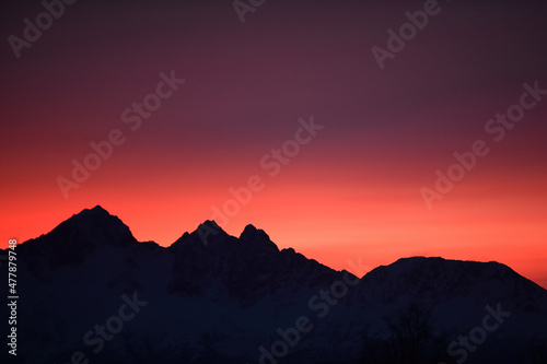 Sunrise colors the skies behind a rugged Alaska mountain range.