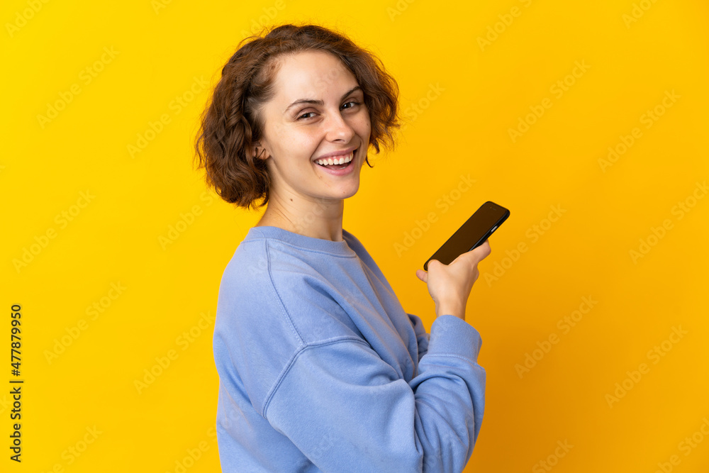 Young English woman isolated on pink background holding a mobile phone and with arms crossed