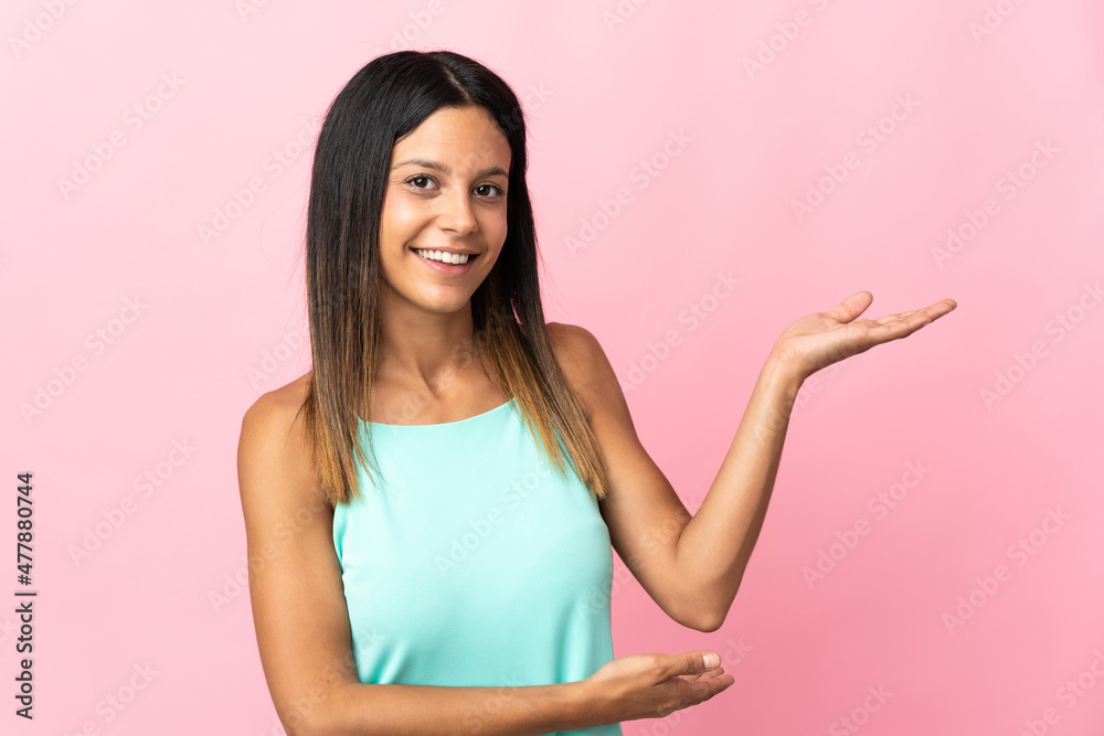 Caucasian girl isolated on pink background extending hands to the side for inviting to come Caucasian girl isolated on pink background extending hands to the side for inviting to come