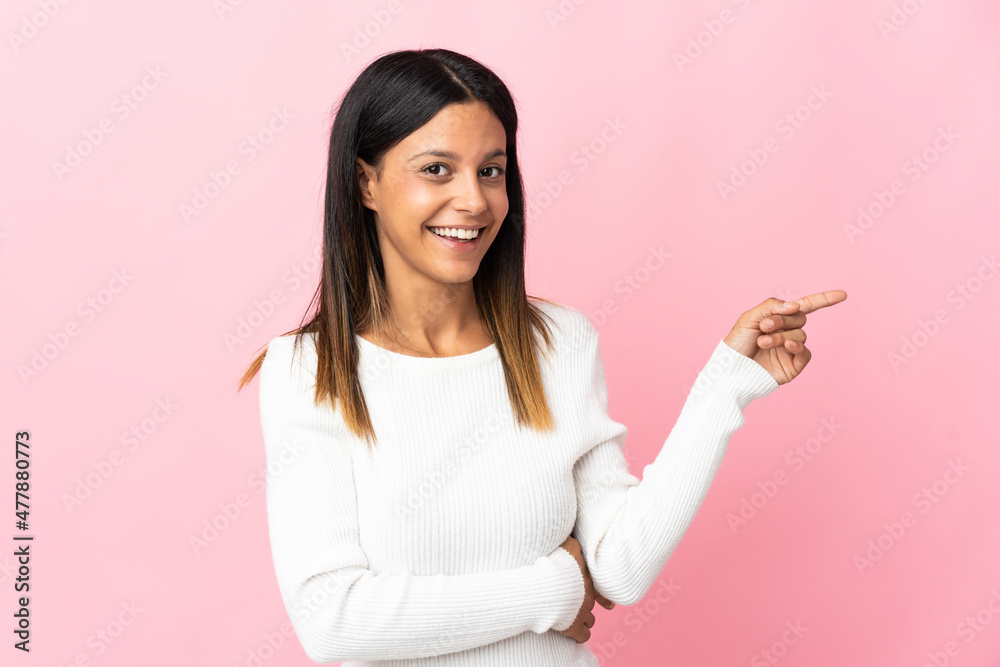 Caucasian girl isolated on pink background pointing finger to the side Caucasian girl isolated on pink background pointing finger to the side