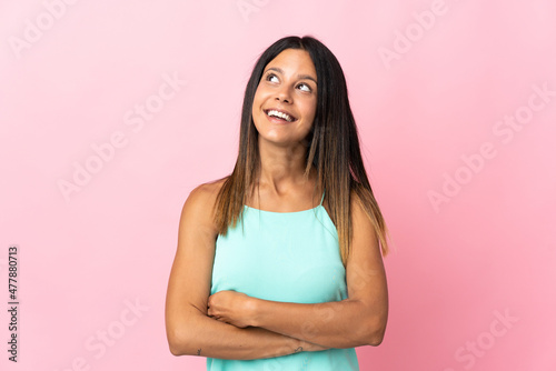 Caucasian girl isolated on pink background looking up while smiling