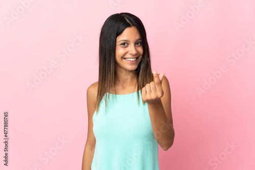 Caucasian girl isolated on pink background making money gesture