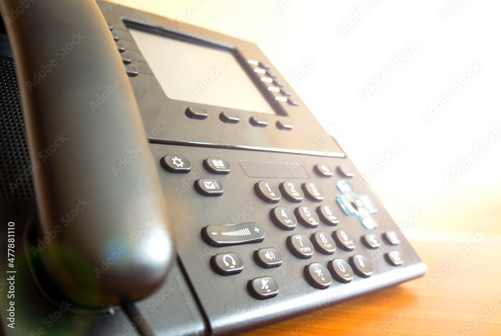The black desktop push-button telephone. IP phone on desk in office. The black desktop push-button telephone. IP phone on desk in office.