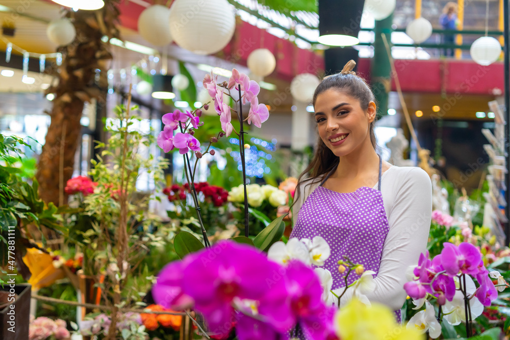 Proud and beautiful florist poses for the camera holding her beautiful and well-groomed orchids Proud and beautiful florist poses for the camera holding her beautiful and well-groomed orchids