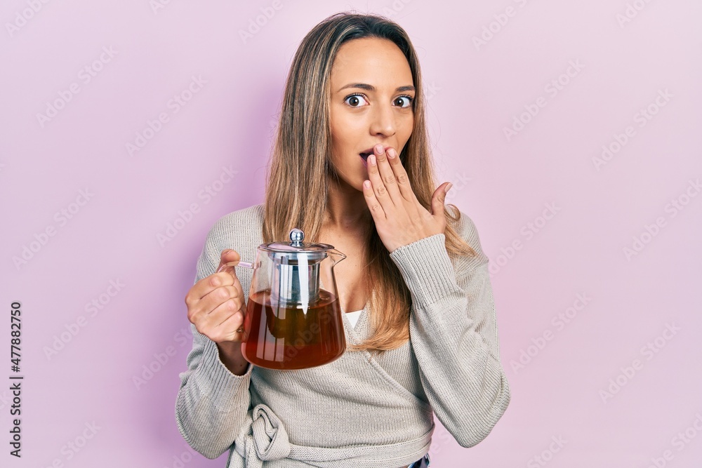 Beautiful hispanic woman wearing traditional tea pot covering mouth with hand, shocked and afraid for mistake. surprised expression Beautiful hispanic woman wearing traditional tea pot covering mouth with hand, shocked and afraid for mistake. surprised expression
