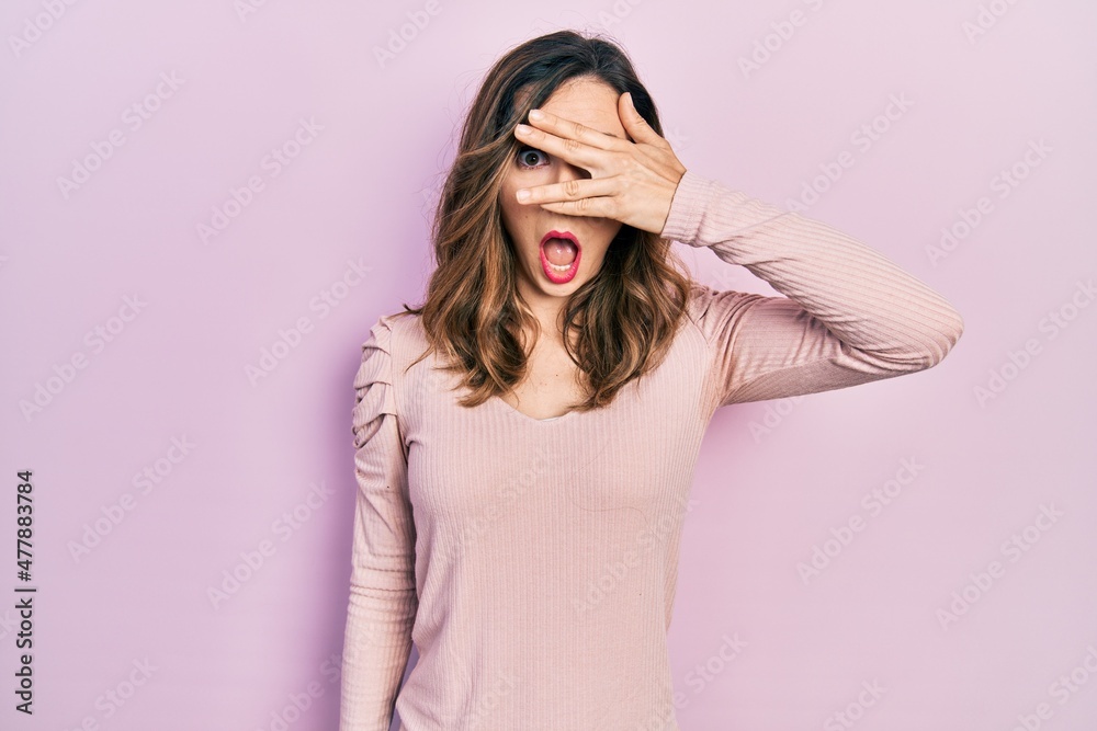 Young hispanic girl wearing casual clothes peeking in shock covering face and eyes with hand, looking through fingers afraid Young hispanic girl wearing casual clothes peeking in shock covering face and eyes with hand, looking through fingers afraid