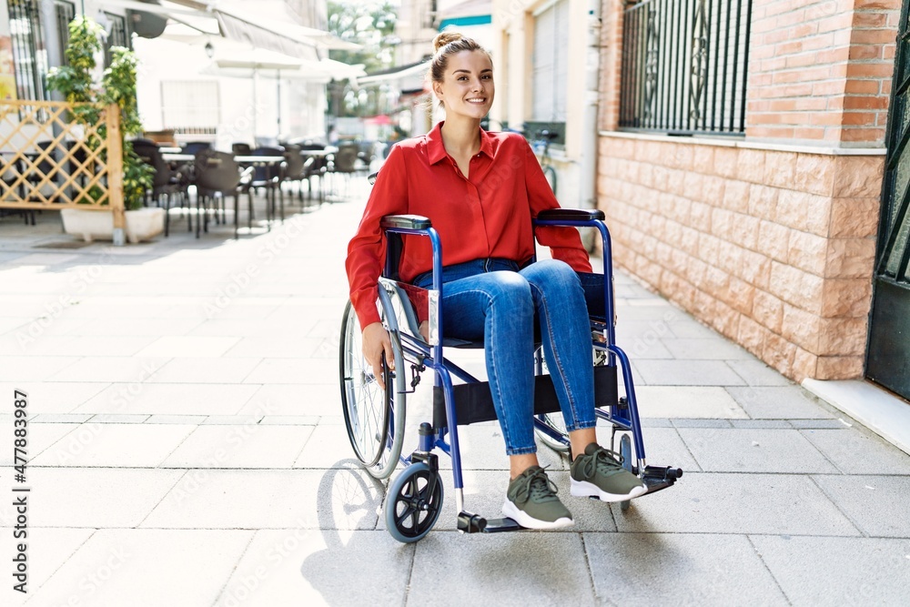 Young woman smiling confident sitting on wheelchair at street