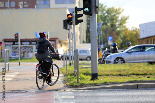 Kobieta na rowerze z plecakiem jedzie ścieżką rowerową w mieście, Wrocław. 