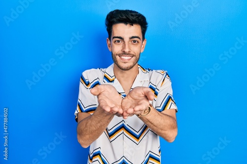 Young hispanic man wearing casual clothes smiling with hands palms together receiving or giving gesture. hold and protection