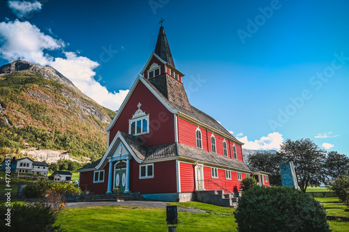 View of the red Olden Church in the village of Olden, Norway on a sunny summer day. Forested mountains are in the background. photo