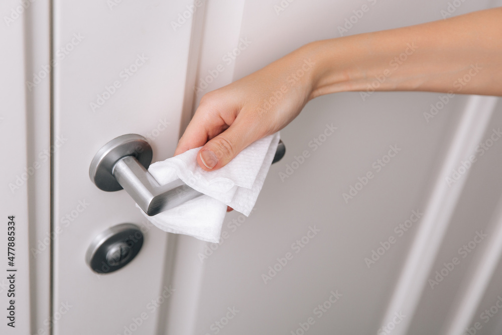 Cleaning door handles with an antiseptic wet wipe and gloves. Woman hand using towel for cleaning home room door link. Sanitize surfaces prevention in hospital and public spaces against corona virus. Cleaning door handles with an antiseptic wet wipe and gloves. Woman hand using towel for cleaning home room door link. Sanitize surfaces prevention in hospital and public spaces against corona virus.