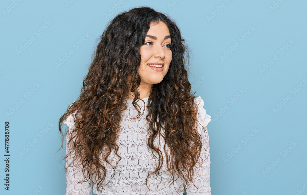 Fototapeta premium Young hispanic girl wearing casual clothes looking away to side with smile on face, natural expression. laughing confident.