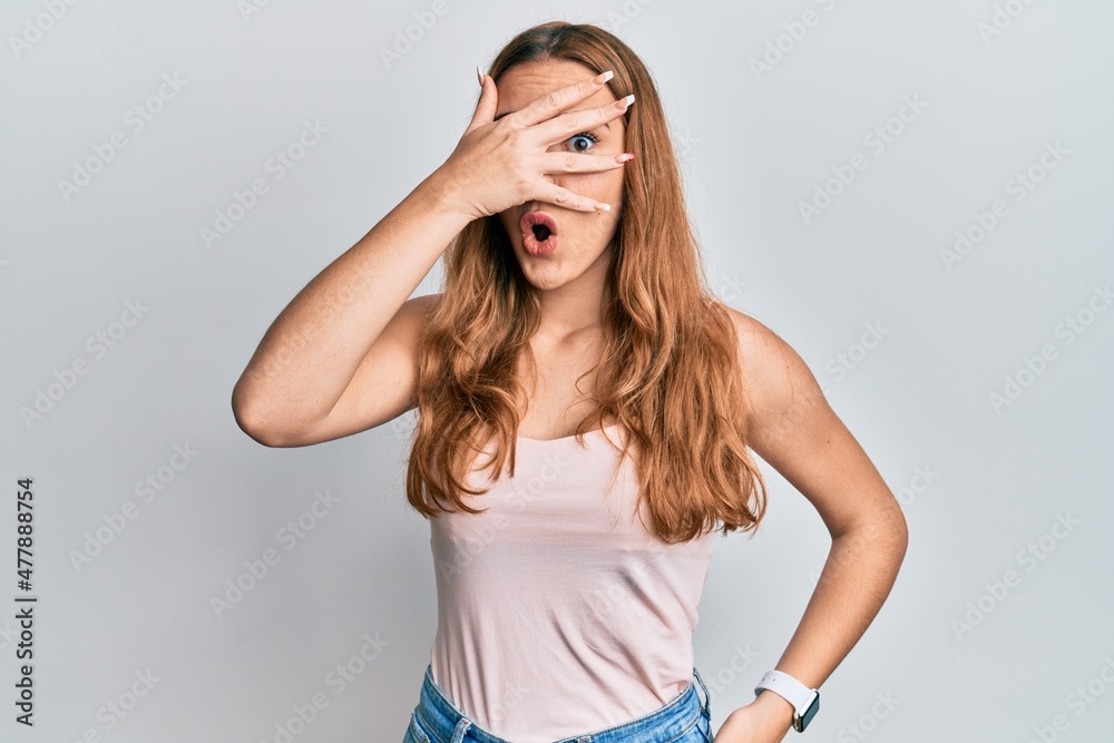 Young blonde woman wearing casual style with sleeveless shirt peeking in shock covering face and eyes with hand, looking through fingers afraid Young blonde woman wearing casual style with sleeveless shirt peeking in shock covering face and eyes with hand, looking through fingers afraid