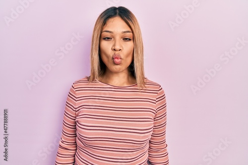 Beautiful hispanic woman wearing casual striped sweater making fish face with lips, crazy and comical gesture. funny expression. © Krakenimages.com