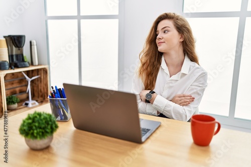 Obraz na plátne Young caucasian woman working at the office using computer laptop looking to the