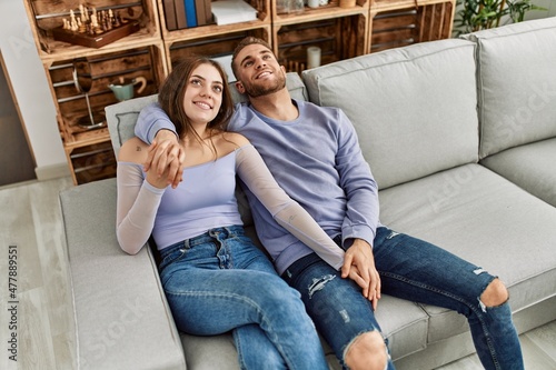 Young caucasian couple smiling happy sitting on the sofa at home.