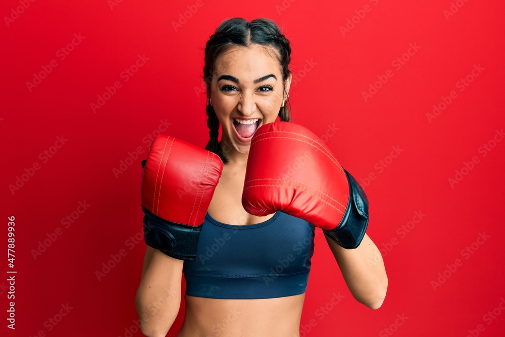 Young brunette girl using boxing gloves celebrating crazy and amazed for success with open eyes screaming excited.