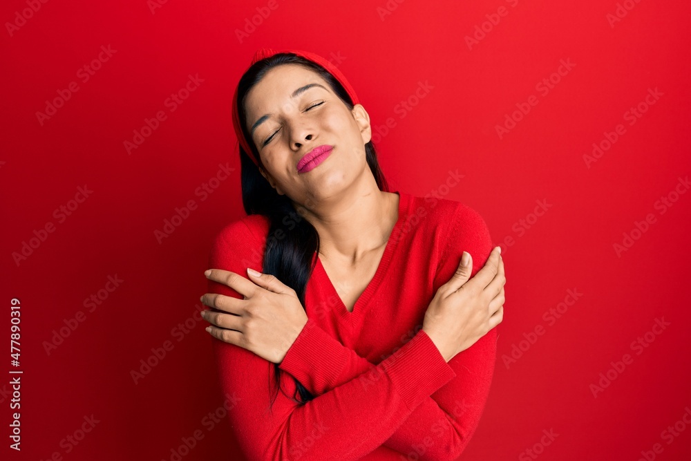 Young latin woman wearing casual clothes hugging oneself happy and positive, smiling confident. self love and self care Young latin woman wearing casual clothes hugging oneself happy and positive, smiling confident. self love and self care