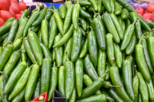 Green chili peppers. Fresh peppers for sale at vegetable market, close up. Boxes full of chili paprika in shop. Chili at the greengrocer's stall. Vegetable. 