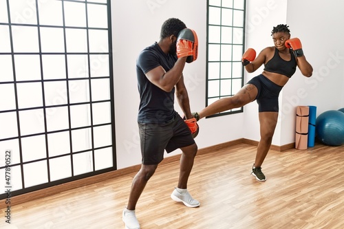 Young african american sporty couple boxing at sport center.