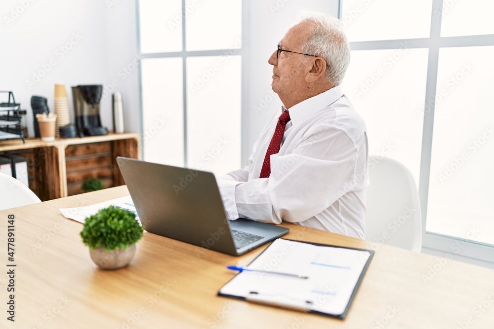 Senior man working at the office using computer laptop looking to side, relax profile pose with natural face and confident smile. Senior man working at the office using computer laptop looking to side, relax profile pose with natural face and confident smile.