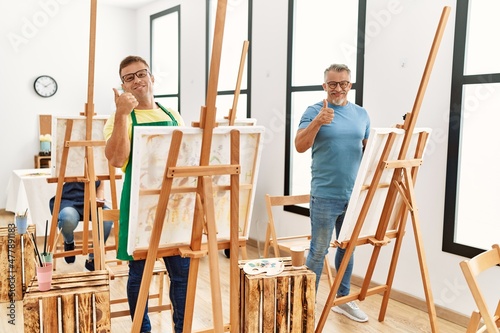 Group of middle age people artist at art studio smiling happy and positive, thumb up doing excellent and approval sign