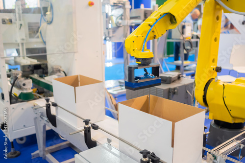 Canvas Print Automatic sorting conveyor system - yellow robotic arm manipulator working with cardboard boxes on conveyor belt