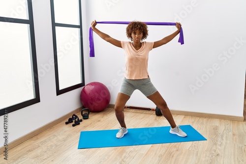 Young african american woman training using elastic band at sport center