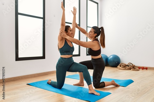 Two women smiling confident training yoga at sport center