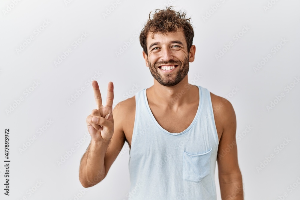 Naklejka premium Young handsome man standing over isolated background showing and pointing up with fingers number two while smiling confident and happy.