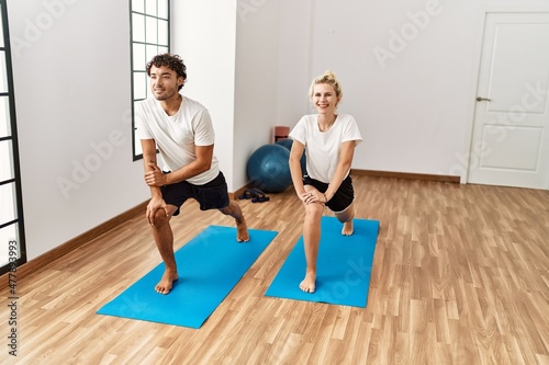 Young couple smiling happy training yoga at sport center.