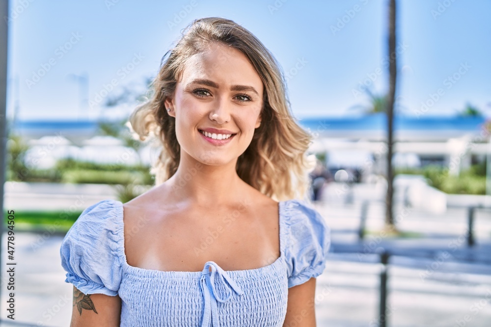 Young blonde girl smiling happy standing at the cityl