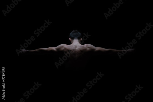Young male athlete posing from the back with arms to the sides showing muscles and strength for advertising or presentation. Copy space